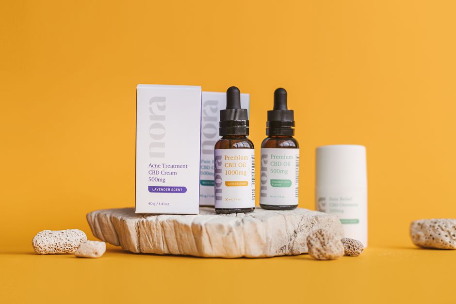 Close-up of CBD oil bottles and cream on a yellow background with natural textures.