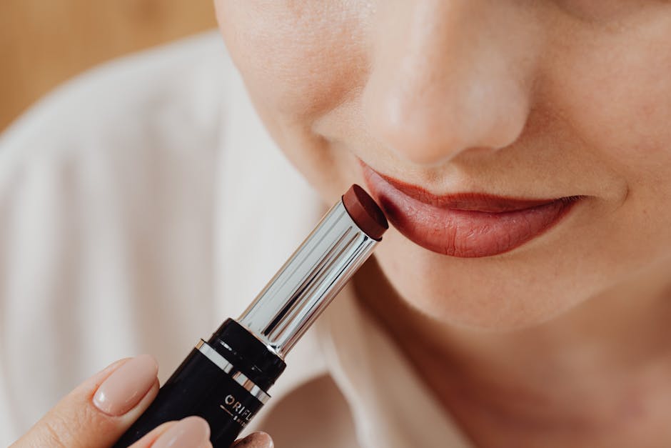 Close-up image of a woman applying red lipstick for makeup and beauty concepts.
