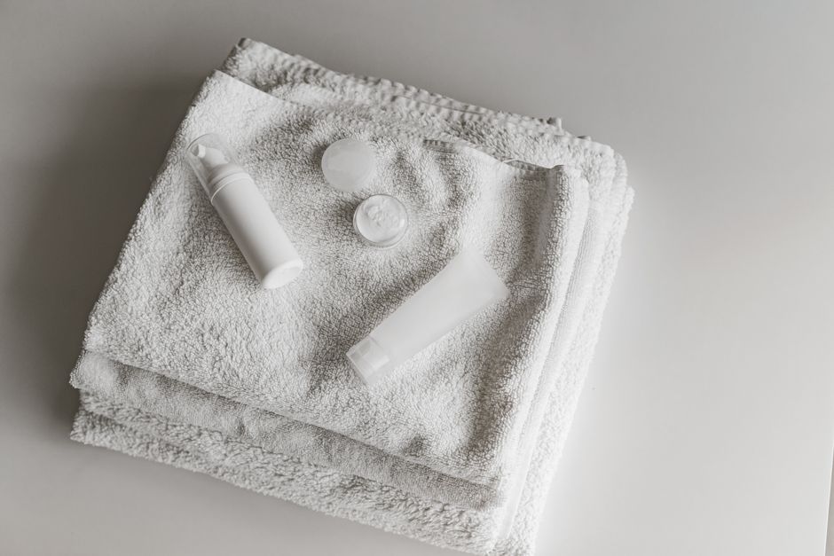 Elegant arrangement of white towels and beauty products in a clean, minimalist setting.