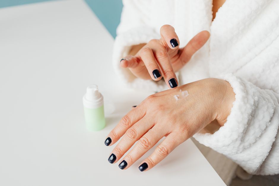 Close-up view of hands applying skincare cream, emphasizing skincare and beauty.