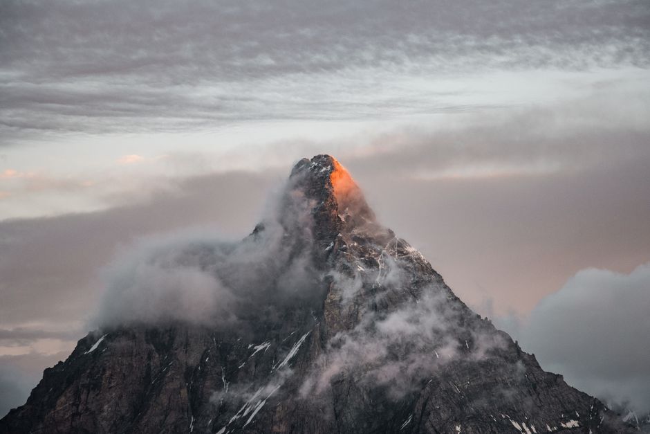 Captivating view of the Matterhorn peak shrouded in clouds during sunset, showcasing nature's beauty.