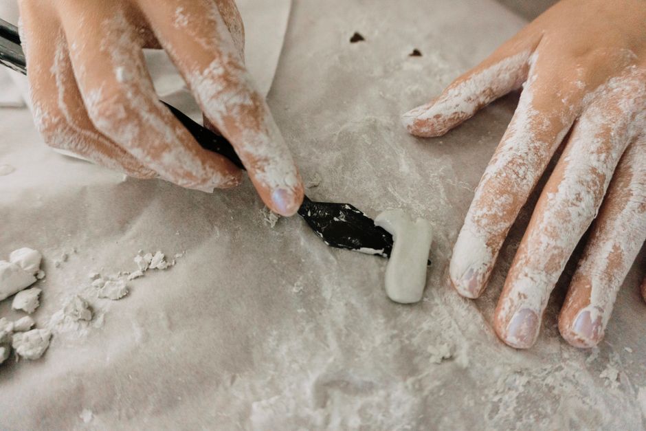 Close-up of hands sculpting clay with precision using tools, highlighting artistic creativity.