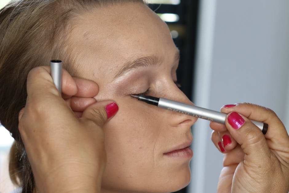 Close-up of a beautician applying eyeliner to a woman's closed eye.