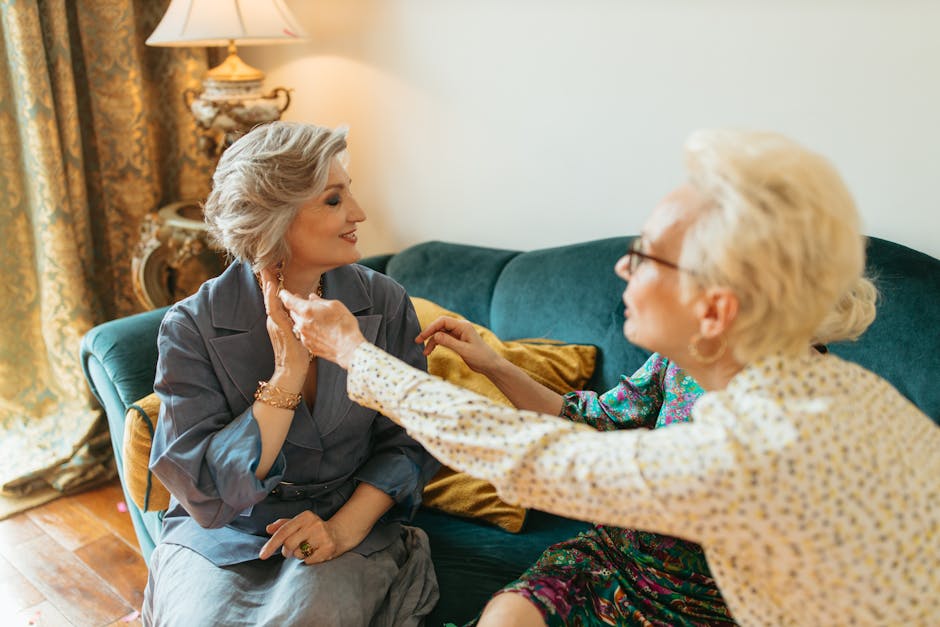 Two elderly women enjoy a warm and personal conversation on a comfortable couch indoors, showcasing companionship and elegant style.
