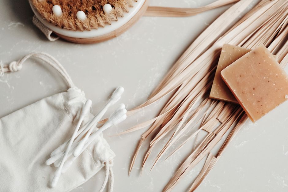 Aesthetic flat lay of natural body care items including soap, dry brush, and cotton swabs promoting a sustainable lifestyle.