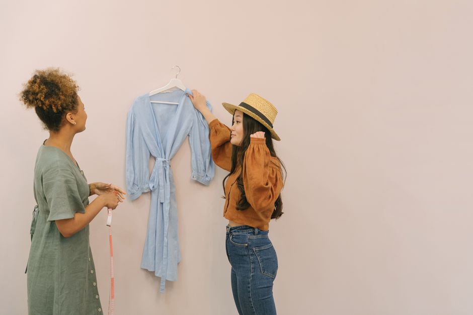 Two women planning a design strategy in a clothing store, discussing a blue dress.