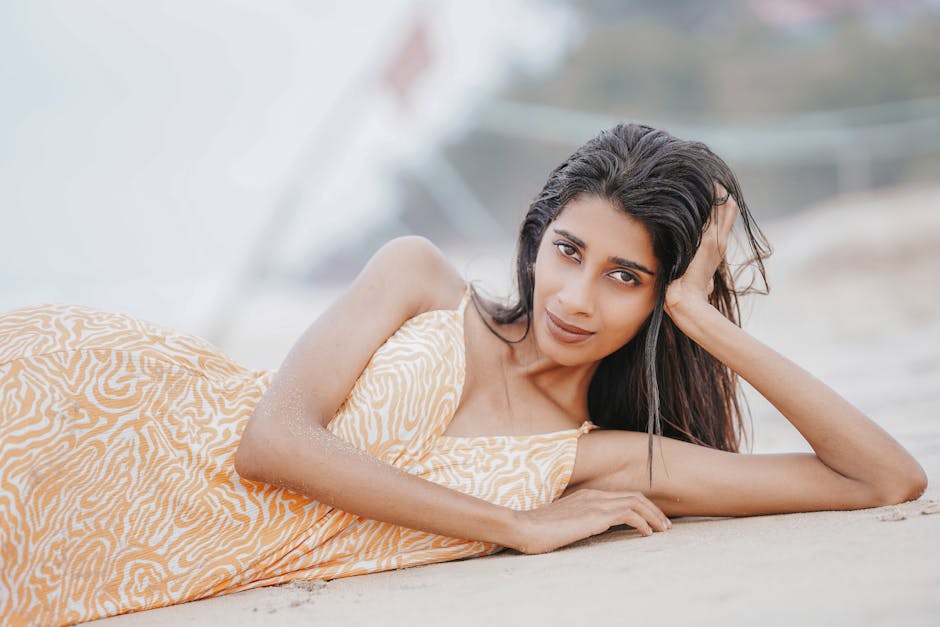 Serene portrait of a woman in summer dress lying on a beach, capturing a moment of relaxation and natural beauty.