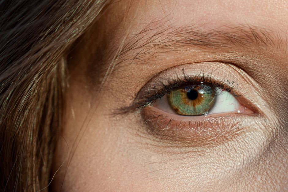 Detailed close-up of a woman's hazel eye with mascara and natural eyelashes.