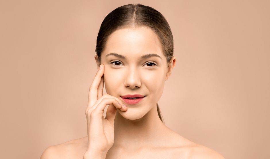 A close-up portrait of a young woman with flawless, radiant skin and a gentle smile, exuding natural beauty.