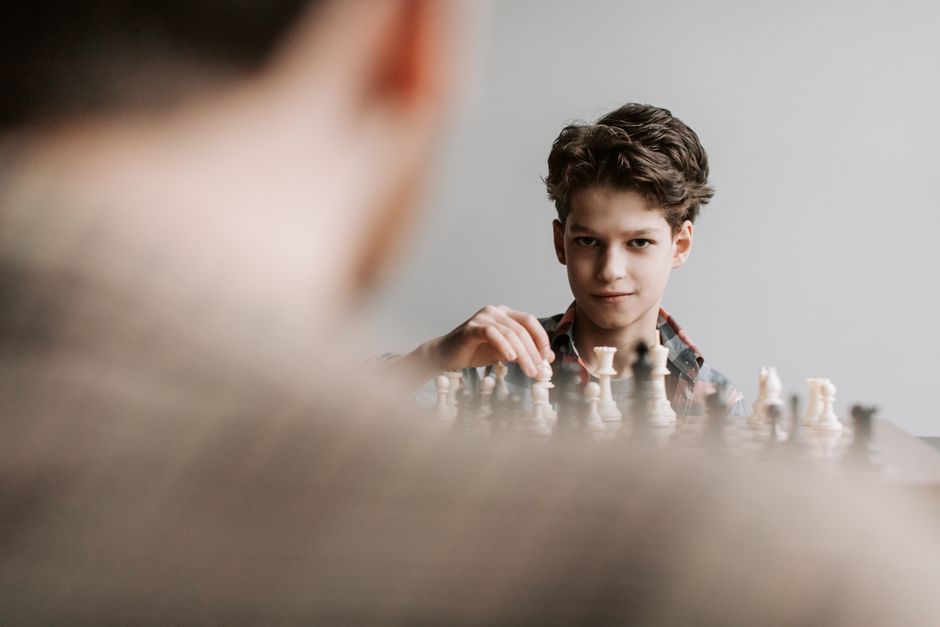 Young boy playing chess, captured in a strategic moment during an intense game indoors.