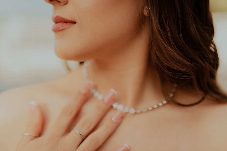 Close-up of a woman touching her diamond necklace with manicured nails.